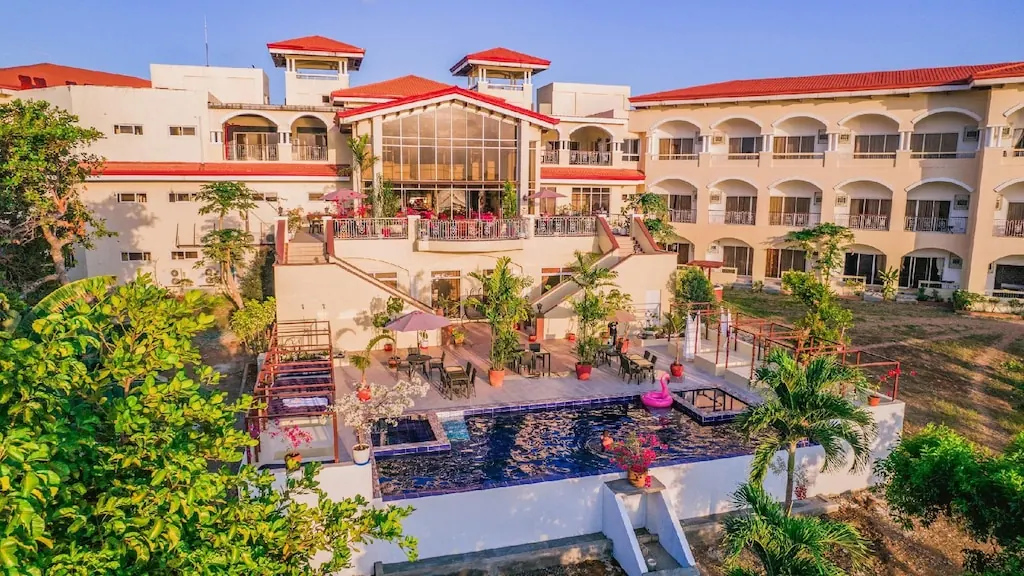 The Palacio from above: red roofs, arched balconies, a pool and palms.