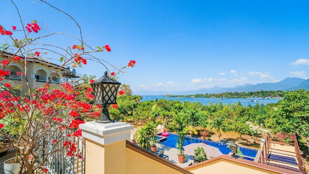 Bougainvillea over a balcony rail, a pool below, and the bay and the hills beyond it.